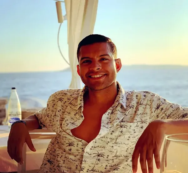 A man sitting behind a sunset, relaxed, with an amazing smile.